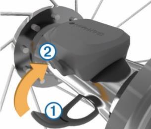 Padoms: Garmin iesaka nostiprināt savu velosipēdu statīvā, kamēr uzstādat sensoru. 1. Novietojiet un turiet ātruma sensoru uz riteņa rumbas augšdaļas; 2.