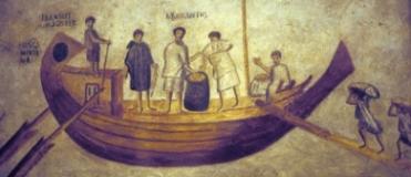 One of the Tiber riverboats, the Isis Giminiana, loading grain at Ostia to be taken to Rome. Her master, Farnaces, superintends the measuring of the grain from his place at the stern.